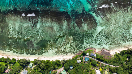 A vibrant aerial of pristine turquoise waters blending into a lush tropical landscape.Praslin, Seychelles.
