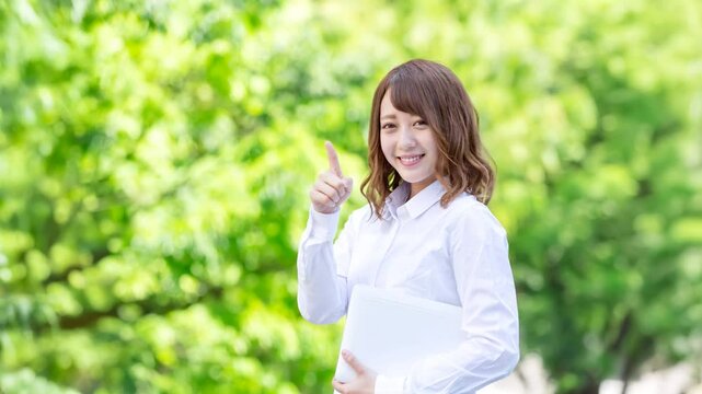 ノートパソコンを持つ若い女性・指差し