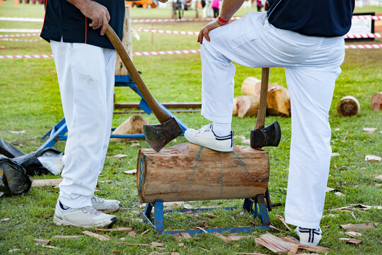 Men resting axe on block for wood splitting competition