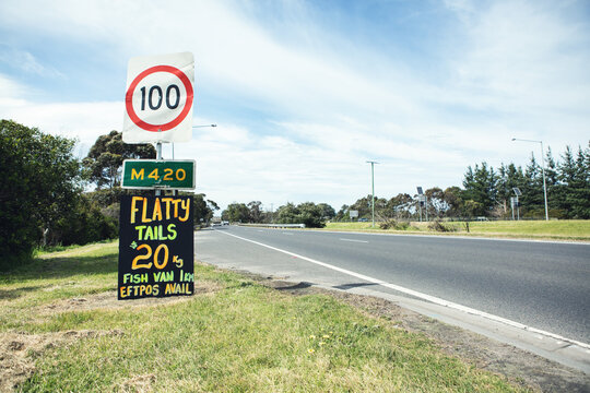 Orange and yellow roadside sign advertising flathead tails horizontal
