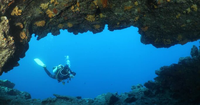 scuba divers exploring a cave underwater with nice light