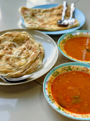 Traditional roti prata served with spicy dhal curry – South Indian breakfast in Malaysia