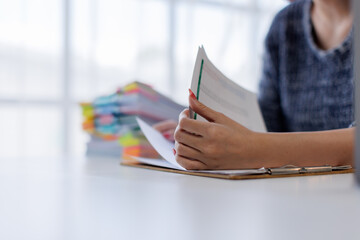 Close up of hands working in Stacks of paper files for searching and checking unfinished document...