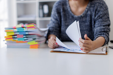Close up of hands working in Stacks of paper files for searching and checking unfinished document...