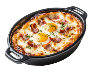 Cheesy baked mashed potatoes topped with bacon and sunny side up egg in black ceramic dish isolated on transparent background