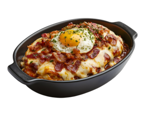 Cheesy baked mashed potatoes topped with bacon and sunny side up egg in black ceramic dish isolated on transparent background