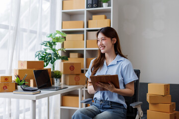 Young attractive asian woman sme owner startup business work happy with box at home prepare parcel...