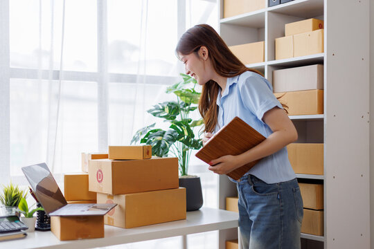 Asian woman entrepreneur taking notes while working on laptop a customer managing orders in her sme small business store. sme supply chain, procurement, omnichannel or coronavirus quarantine concept.
 - Powered by Adobe