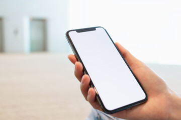 Hand holding smartphone with blank screen for graphic display montage on outdoors background, mockup display for lifestyle and wireless technology.