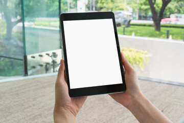 Hand holding digital tablet with blank screen for graphic display montage in the building area, mockup display for lifestyle and wireless technology.