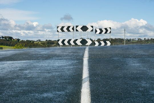 A road leading up to a directional sign at a T intersection