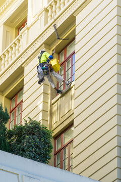 A window repairer hanging on the outside of a tall building