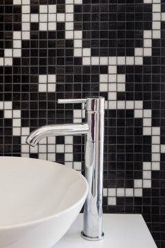 bathroom sink with chrome tap and black and white mosaic tiles