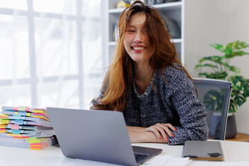 Portrait of young asia business woman sitting on desk with laptop under stress from too much work...