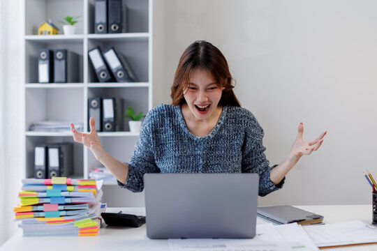 Portrait of young asia business woman sitting on desk with laptop under stress from too much work in the office.deadline job shouting crazy work overwhelmed, Mental Health in the workplace.
