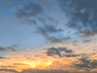 Fototapeta premium Dramatic cloudy sky during sunset with warm orange and cool blue tones blending together, capturing a peaceful and moody atmosphere.