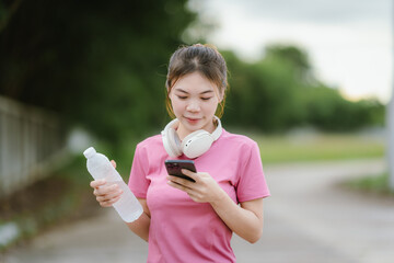 
A young woman in pink athletic wear pauses, seemingly catching her breath after exercise, looking...