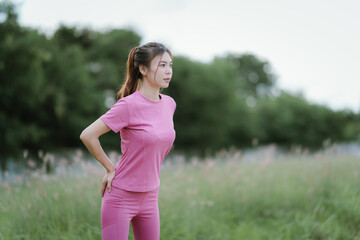 
A young woman in pink athletic wear pauses, seemingly catching her breath after exercise, looking...