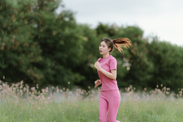 
A young woman in pink athletic wear pauses, seemingly catching her breath after exercise, looking...