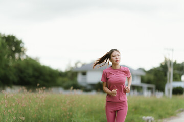 
A young woman in pink athletic wear pauses, seemingly catching her breath after exercise, looking...