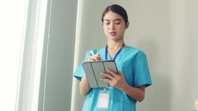 Professional female doctor is standing and recording various medical data on a tablet and thinking and planning her work.