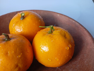 Oranges neatly arranged in a clay bowl, presented against a clean background, ideal for health, food and minimalist themes.