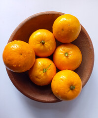 Oranges neatly arranged in a clay bowl, presented against a clean background, ideal for health, food and minimalist themes.