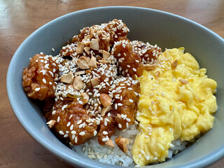 A bowl of rice with scrambled egg, chicken cubes and sesame seed