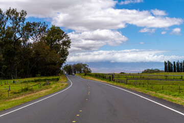 Scenic road winds through lush greenery under a partly cloudy sky.
