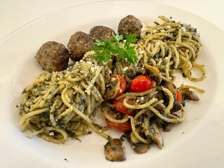 A delicious Pesto spaghetti with meatballs, mushroom, and tomato slices