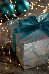 Teal ribbon adorns a sparkling silver gift box.