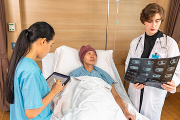 Asian man cancer patient visiting young female doctor for medical consultation in clinic. male patient struggling with cancer, healthcare. Medicine concept.Female doctor explaining xray to patient.