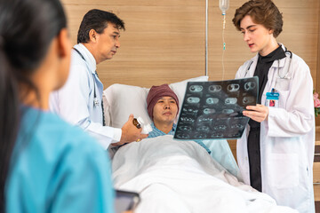 Asian man cancer patient visiting young female doctor for medical consultation in clinic. male patient struggling with cancer, healthcare. Medicine concept.Female doctor explaining xray to patient.