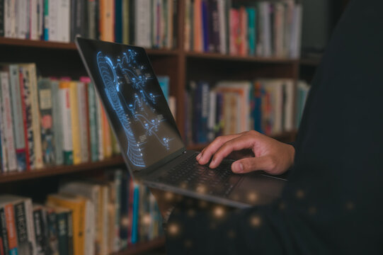 Man typing on computer laptop in library at home, using laptop for work or study. blurred Book filled shelves background