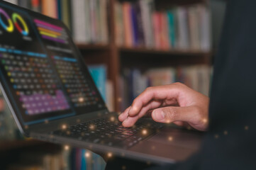 Man typing on computer laptop in library at home, using laptop for work or study. blurred Book...
