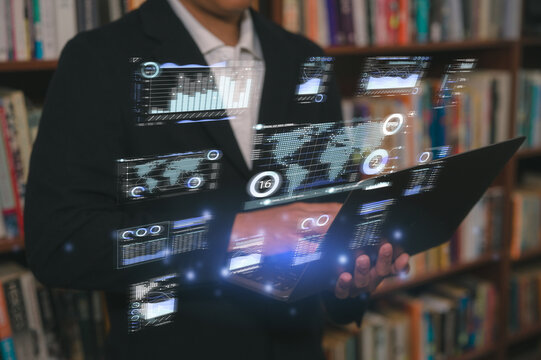 Man typing on computer laptop in library at home, using laptop for work or study data analysis in business or research on data charts. blurred Book filled shelves background