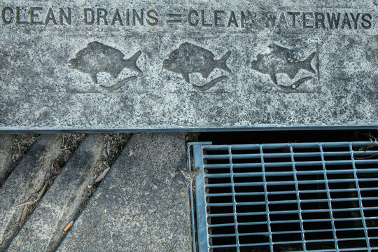 Clean drains = clean waterways written on gutter beside road