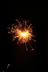 Fototapeta premium Yellow sparks fly on a black background, layered with grain, noise, and glowing effects to give a gritty, cinematic feel full of motion, contrast, and intense visual energy.