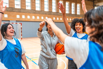 Female basketball team celebrating victory in gymnasium