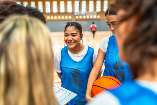Female basketball players discussing game strategy in gym