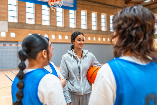 Female basketball coach talking to team during training in gym - Powered by Adobe
