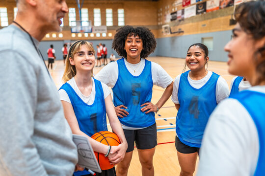 Female basketball team listening to coach instructions during training