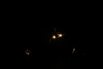 Yellow sparks fly on a black background, layered with grain, noise, and glowing effects to give a...