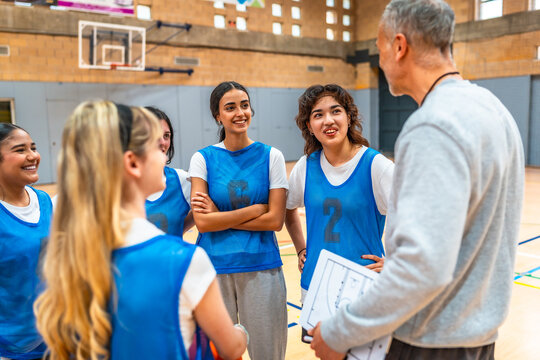 Basketball coach explaining strategy to female high school team