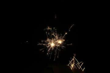 Yellow sparks fly on a black background, layered with grain, noise, and glowing effects to give a...
