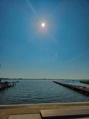 A sunny jetty extends into a tranquil lake, illuminated by the bright sun. The Dümmer, also...
