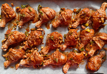 Fresh raw marinated chicken thigh drumstick, sliced and scored from the sides, ready for oven on...