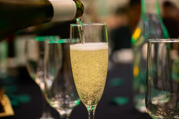 pouring sparkling wine, champagne style, at party, evening celebration