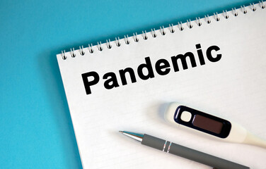 Pandemic - text on a notepad. Lie a pen and a medical thermometer