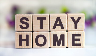 STAY HOME - text on wooden cubes on a floral background with tulip buds